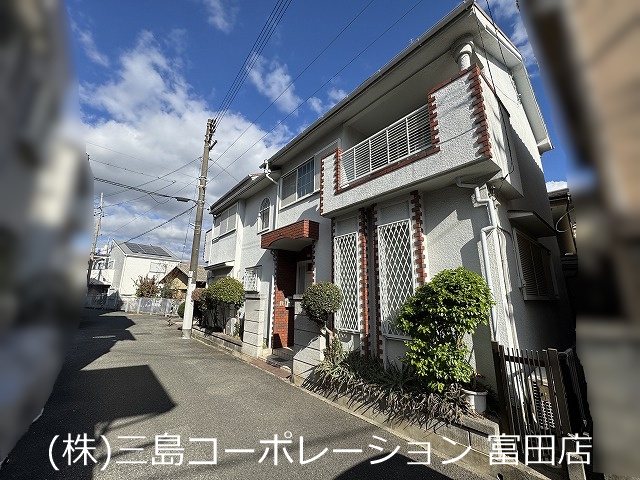 高槻市赤大路町　売土地 落ち着いた住宅街に佇む、堂々とした外観の建物です。青い空が広がる明るい日差しの中で、静かな暮らしが想像できます。
