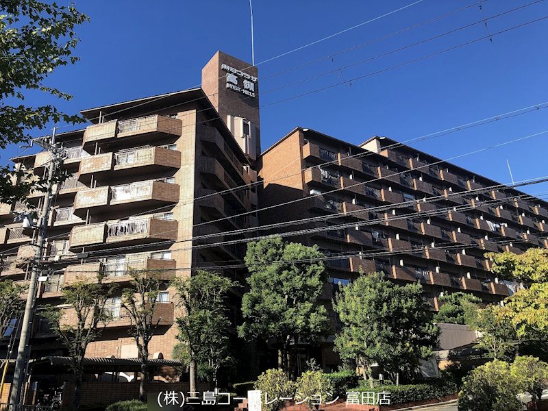 青空に映える重厚な外観が印象的なマンション。豊かな緑に囲まれた落ち着きのある住環境が魅力です。