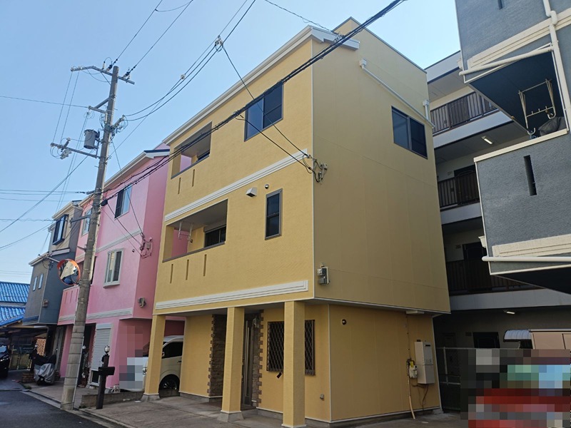 摂津市別府2丁目　中古一戸建  鮮やかな外観が目を引く3階建ての建物です。駐車スペースも確保されており、都市での生活をサポートします。